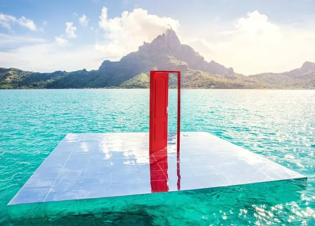Red sculptural frame overlooking tropical lagoon, minimal, geometric, vibrant