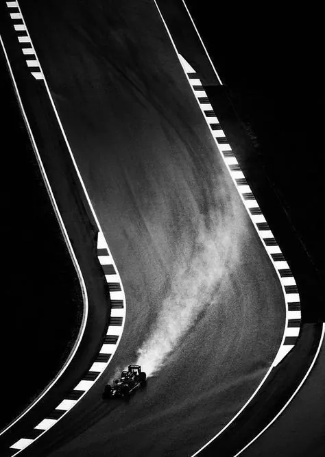 Overhead view of car on curved road with lane markings, photographic, geometric, monochrome
