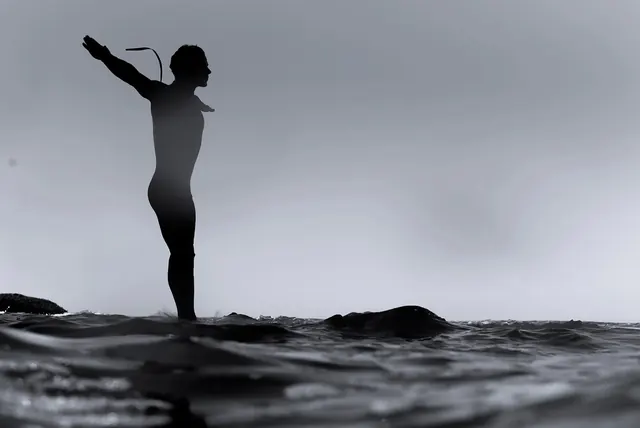 Surfer in wetsuit preparing to paddle, photographic, minimalist, monochrome