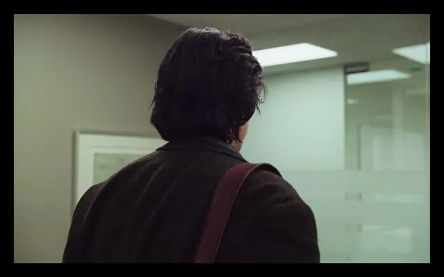 Man viewed from behind in modern office hallway, photographic, editorial, muted