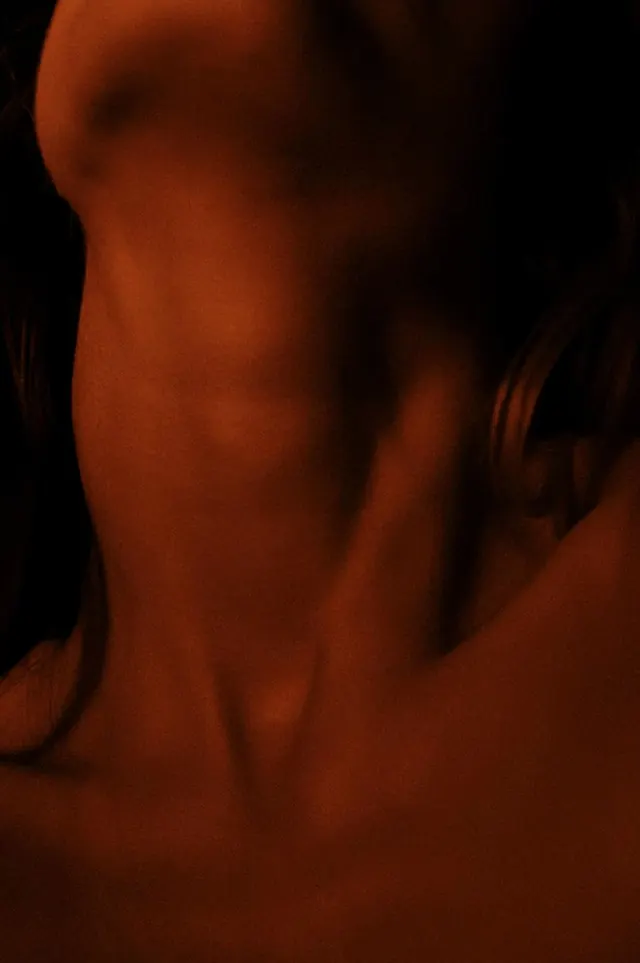 Warm dramatic close-up of neck and shoulders, minimal, photographic, dark