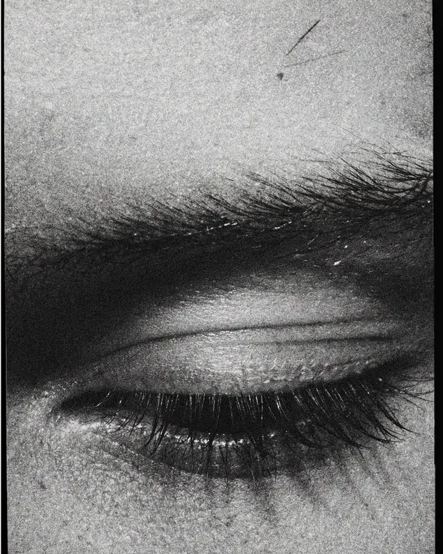 Grainy closed-eye macro portrait, editorial, photographic, monochrome