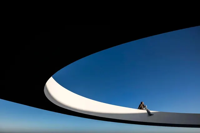 Person on Curved Concrete Architecture at Blue Hour, minimal, editorial, cool