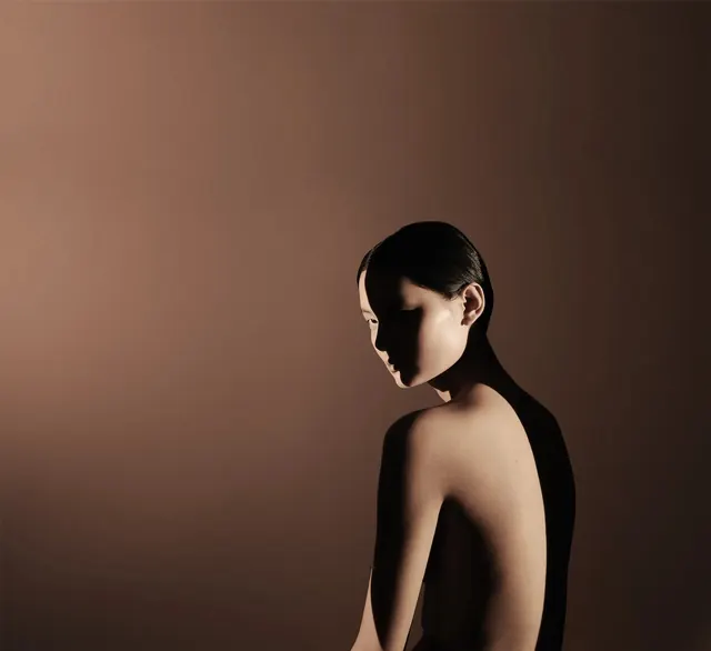 Chiaroscuro over-shoulder portrait, photographic, editorial, warm