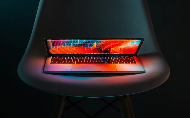 Glowing laptop on Eames chair, minimal, photographic, dark