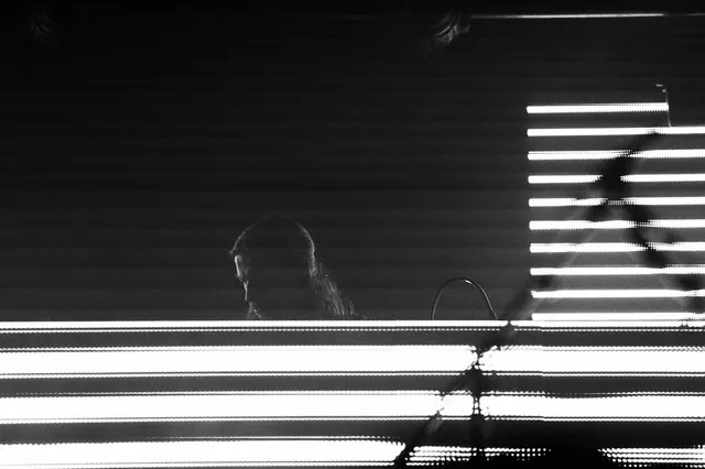 DJ silhouette against light bars, minimal, photographic, monochrome