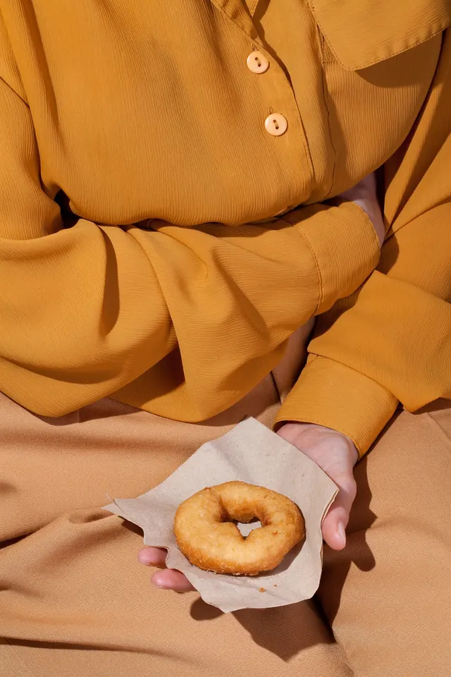 Golden shirt with donut snack styled flat lay, editorial, photographic, warm