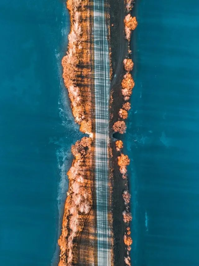 Aerial road through coastal landscape, photographic, minimalist, cool