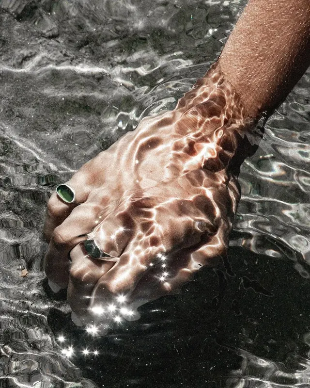 Hand holding freshwater fish underwater closeup, photographic, editorial, warm
