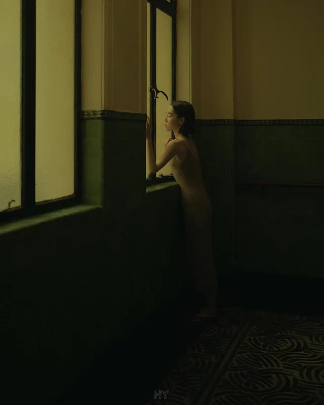 Dimly-lit portrait in warm beige room, photographic, minimal, warm