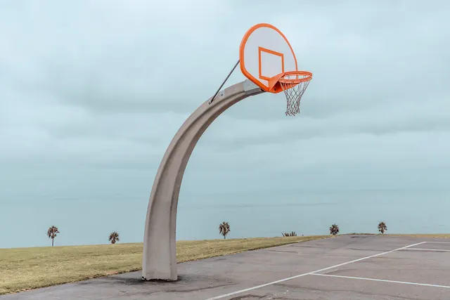 Sculptural basketball hoop in flat desert landscape, photographic, minimalist, cool
