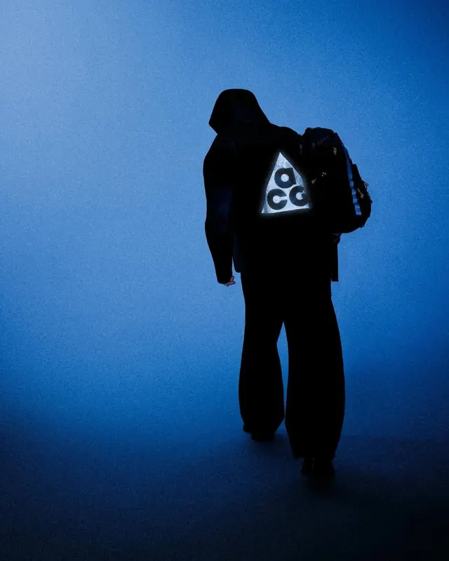 Silhouetted figure with geometric light symbol, photographic, minimal, cool