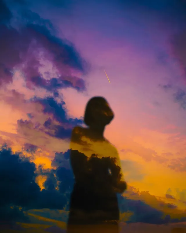 Silhouette figure against colorful sunset sky, photographic, organic, vibrant