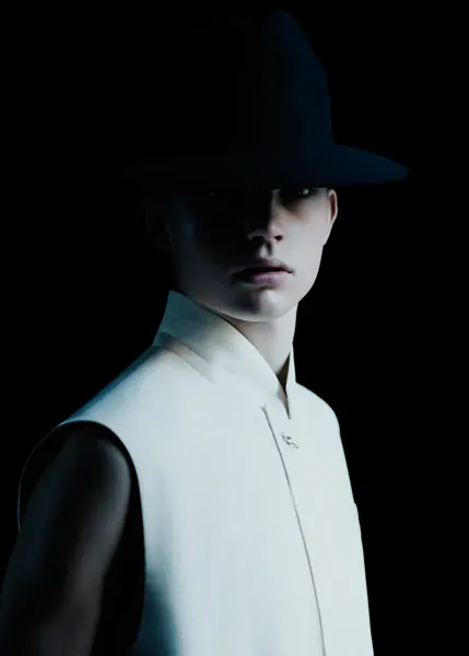 Editorial portrait with dark hat and lighting, photographic, minimal, dark