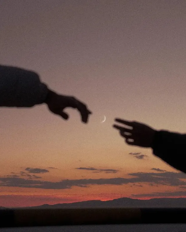 Hands reaching toward crescent moon at sunset, photographic, minimalist, warm