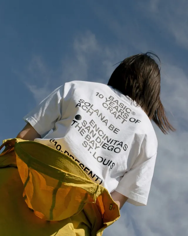 Youth wearing graphic t-shirt and yellow technical outerwear, photographic, light-mode, vibrant