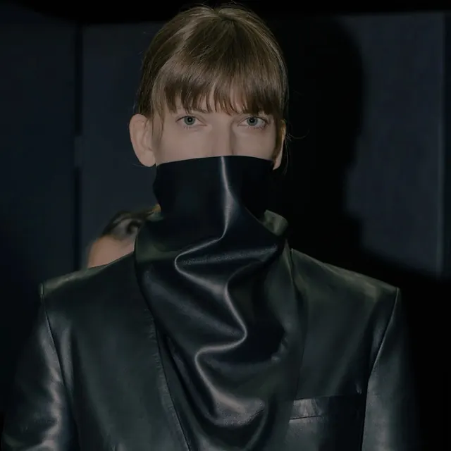 Moody portrait with sculptural high-collar garment, photographic, editorial, dark