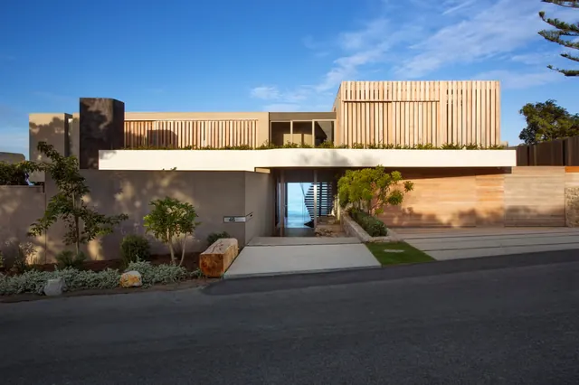 Modern coastal architecture with corrugated metal and stone facade, minimal, technical, warm