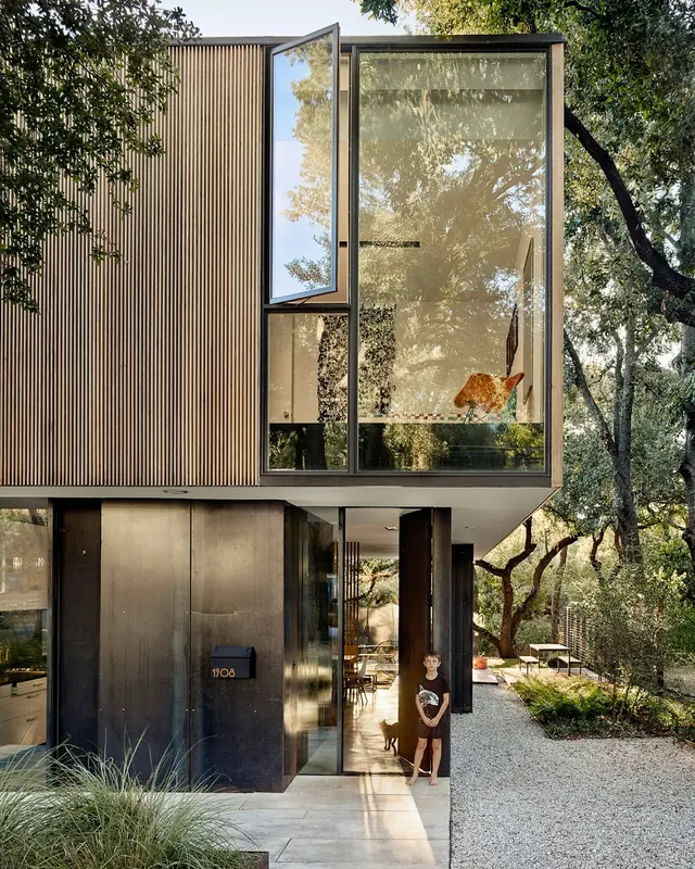 Modernist prefab house with corrugated siding and large windows, minimal, technical, earthy