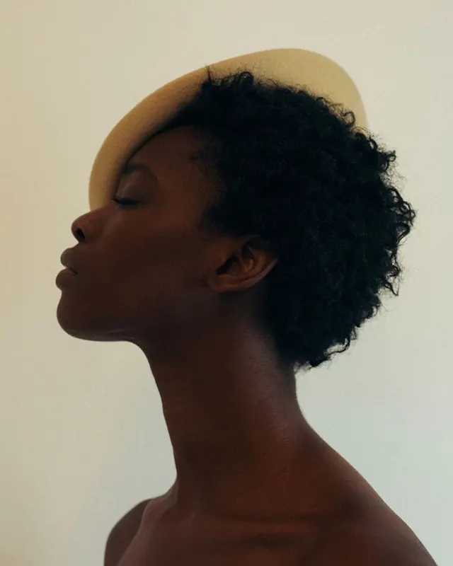 Profile portrait against cream background, photographic, minimal, warm