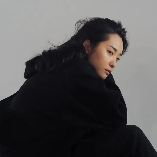Portrait with dark clothing against neutral background, photographic, minimal, dark