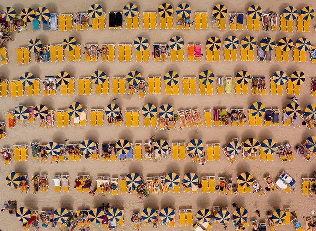 Aerial beach scene with yellow umbrellas, photographic, minimalist, warm