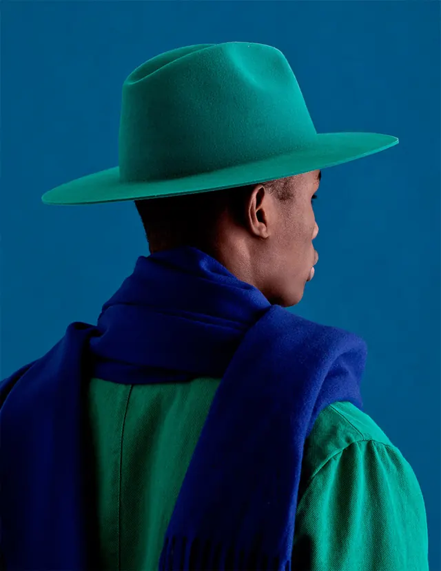 Fashion portrait with teal cowboy hat and layered color blocking, photographic, minimal, cool