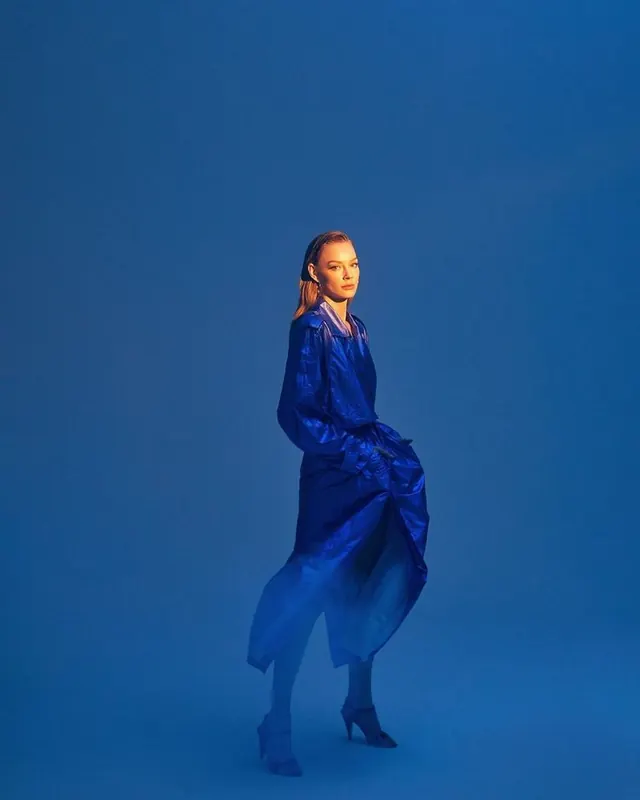 Woman in blue jacket against monochromatic blue background, photographic, minimal, cool
