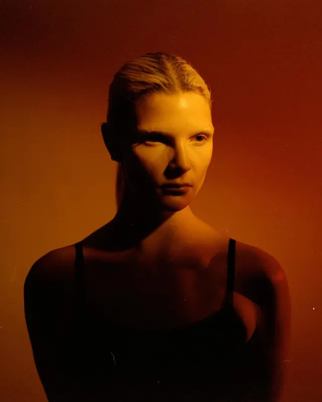 Dramatic warm-toned portrait with shadow side lighting, photographic, minimal, dark