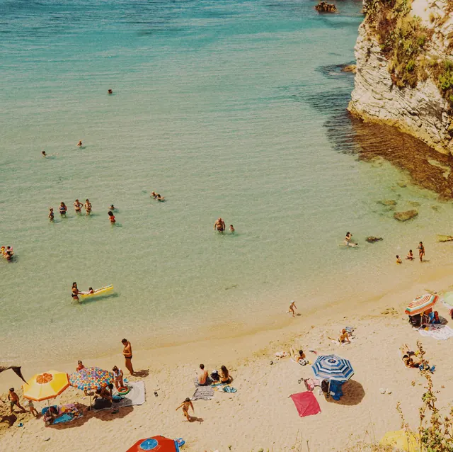 Aerial beach scene with swimmers and umbrellas, photographic, organic, vibrant