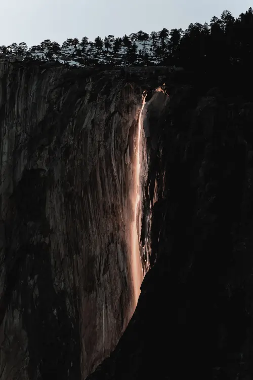 Rocky cliff face with warm light streak, photographic, dark-mode, dark