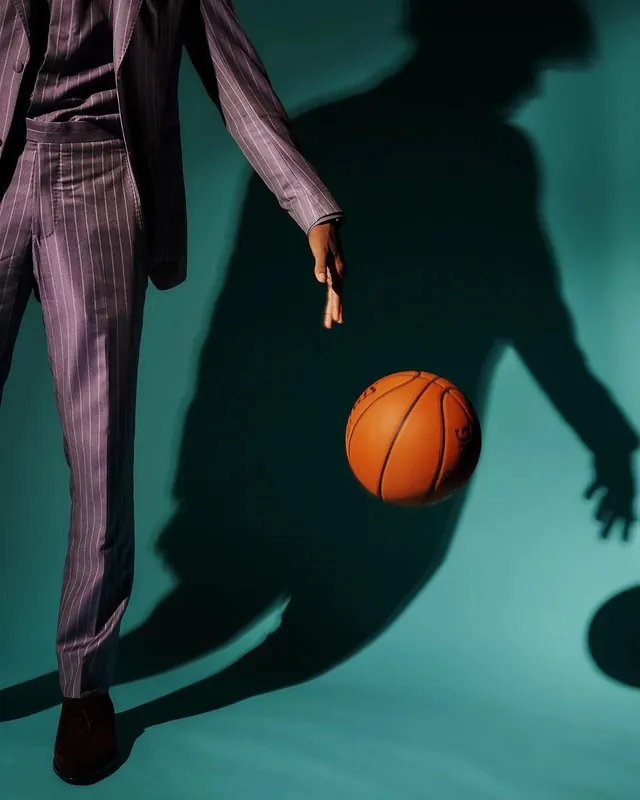 Person in purple suit with basketball and shadow on teal background, photographic, editorial, vibrant