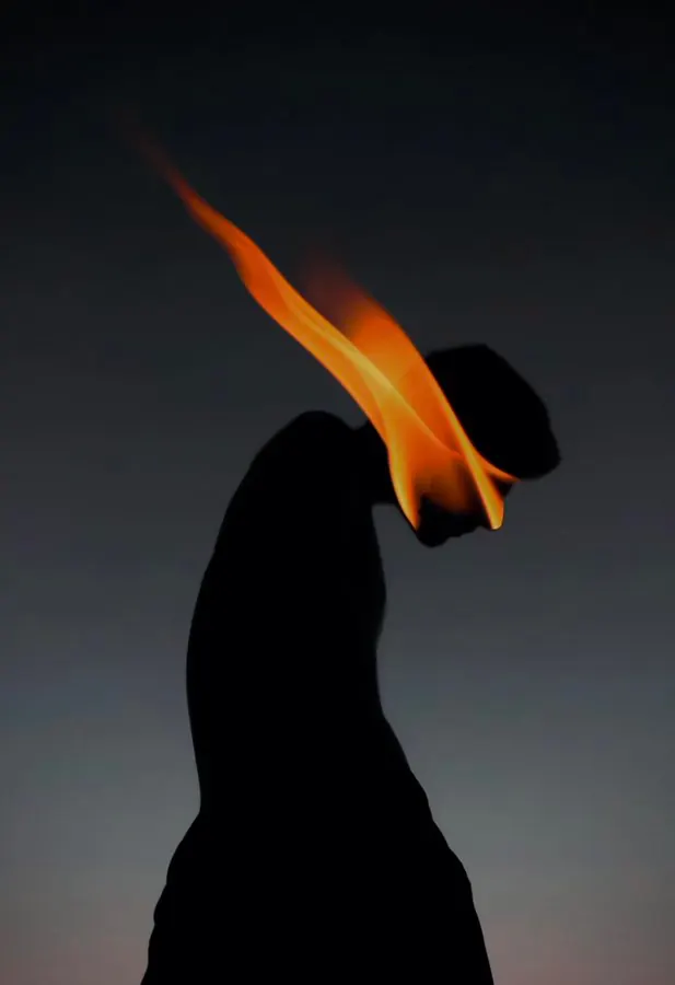 Silhouette with flame element against gradient sky, photographic, abstract, dark