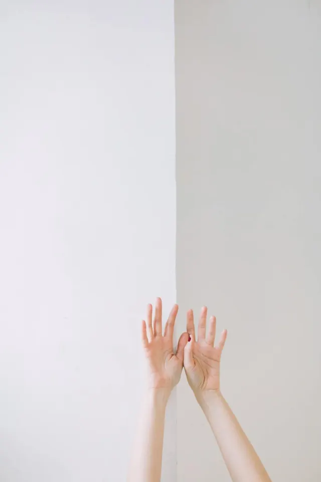 Two hands raised against split wall, minimalist, photographic, light