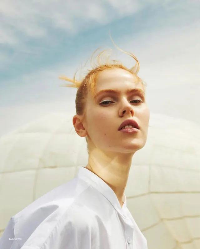Portrait with wind-swept hair and sky backdrop, photographic, minimal, light