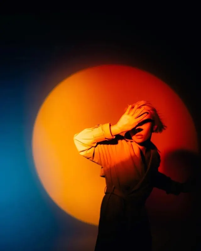 Sun-silhouetted portrait with blue-to-orange glow, photographic, dark-mode, dark