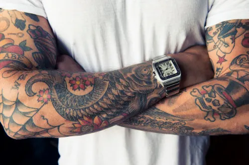 Tattooed arm with watch fashion photograph, photographic, minimal, warm