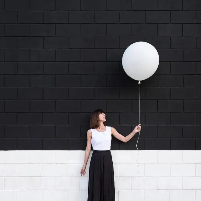 Balloon portrait on split brick wall, minimal, photographic, monochrome