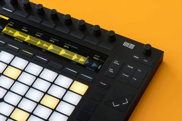 Ableton Push on orange surface, technical, minimal, vibrant