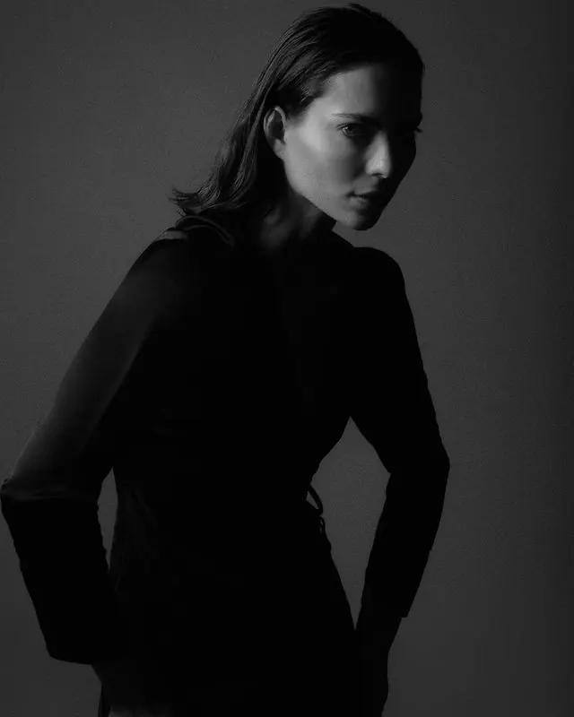 Low-key fashion portrait over shoulder, editorial, photographic, monochrome