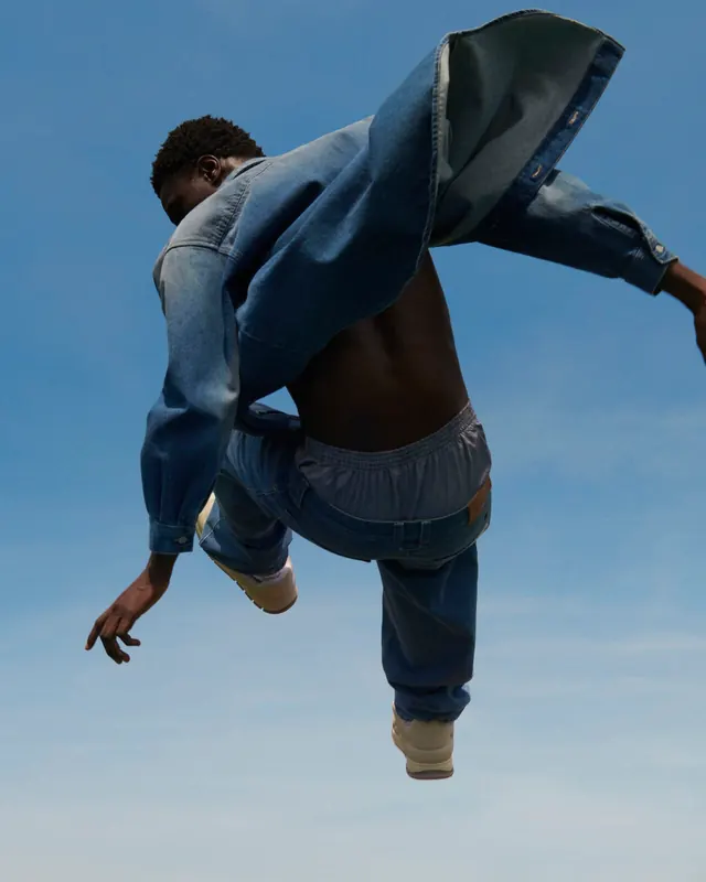 Denim leap against blue sky, photographic, editorial, cool