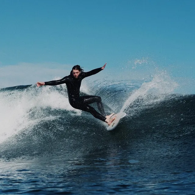 Surfer carving a blue ocean wave, photographic, minimal, cool