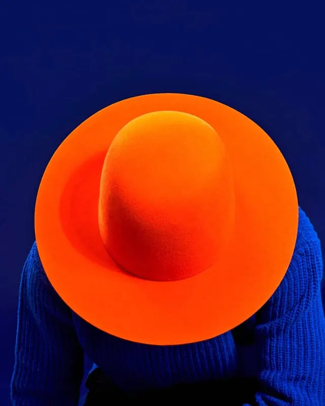 Orange hat on cobalt ribbed knit, minimal, photographic, vibrant