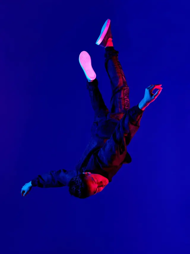 Inverted figure in magenta-cyan gel light, photographic, minimal, dark