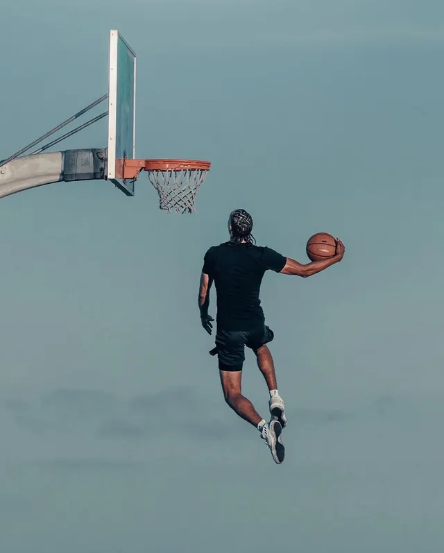 Basketball dunk against pale sky, photographic, minimal, cool