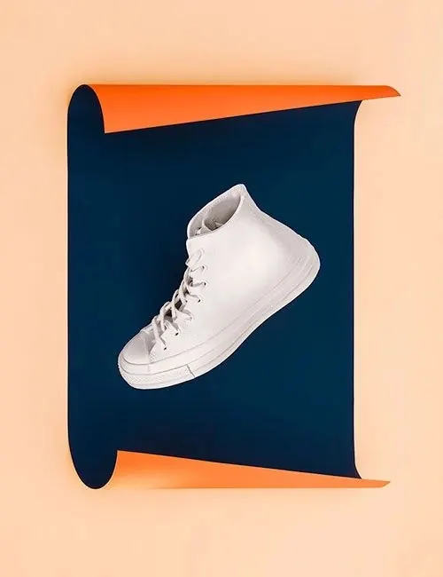 White sneaker on curled paper strips, minimal, playful, light