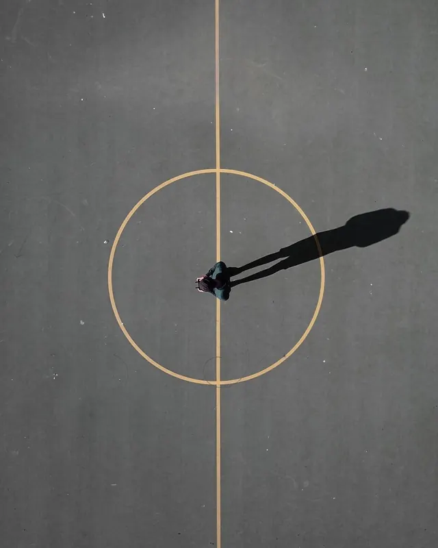 Top-down figure on painted court circle, minimal, photographic, muted