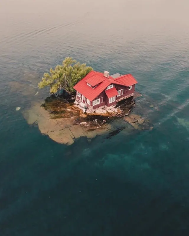Aerial tiny island house on teal water, photographic, minimal, cool