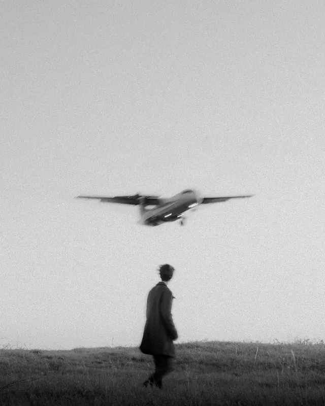 Grainy figure and low-flying plane, photographic, monochrome, monochrome