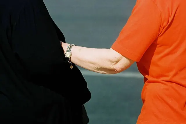Orange sleeve reaching to black coat, photographic, minimal, vibrant